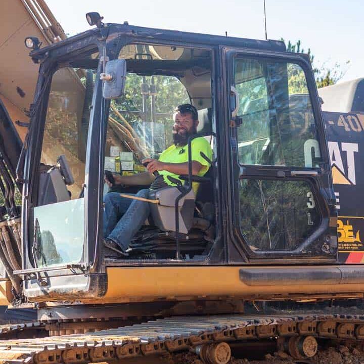 A man sitting in the cab of a piece of equipment smiling at the camera