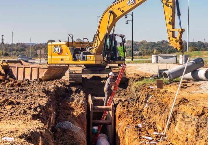 A man going up a ladder with excavation equipment in the background