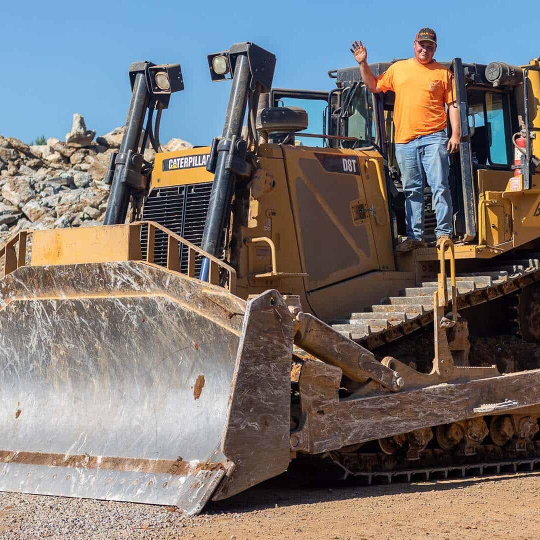 a man standing on a a bull dozer waving