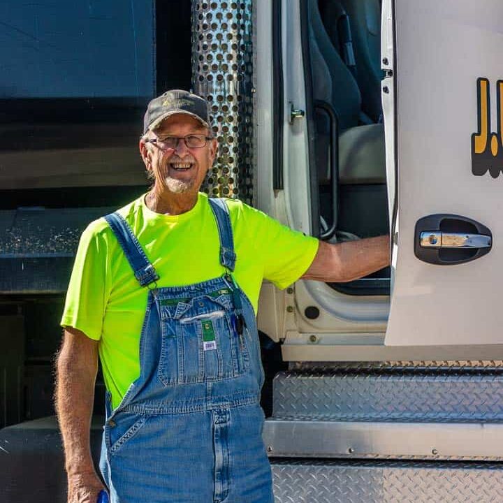 A man smiling while getting out of a dump truck